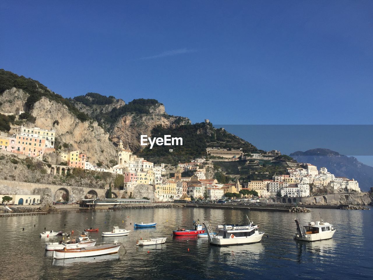 Boats moored at waterfront against clear sky