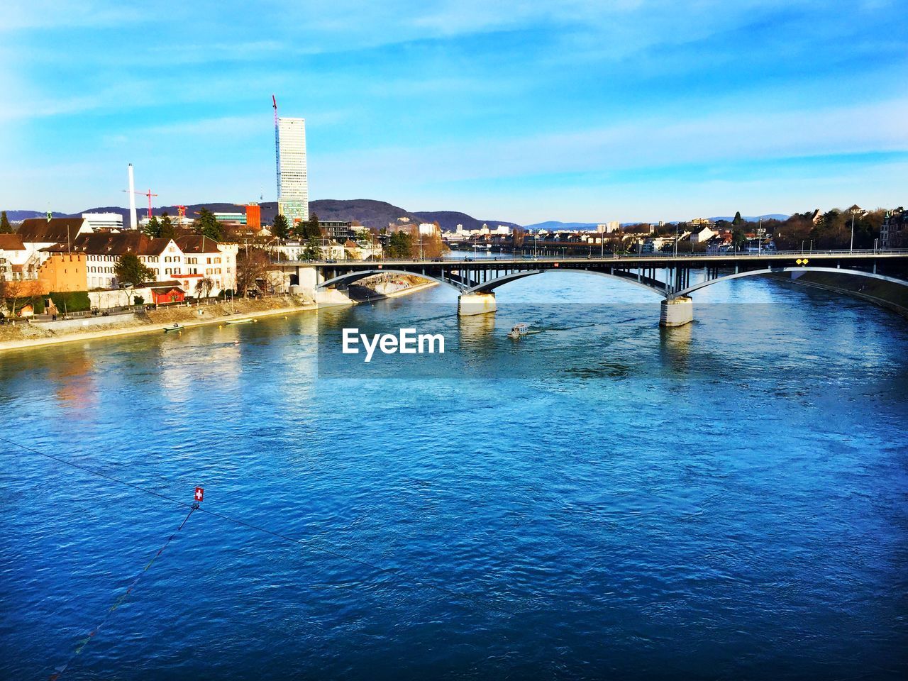 Bridge over river in city against blue sky