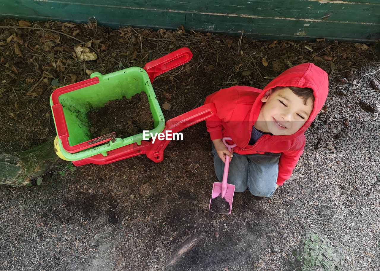 Child plays with wheel barrow and soil