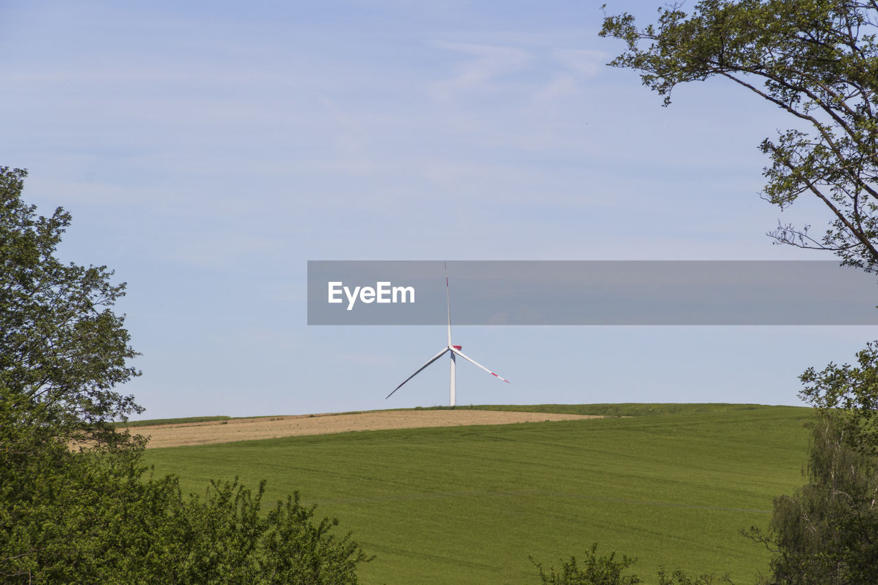 Low angle view of windmill on field against sky