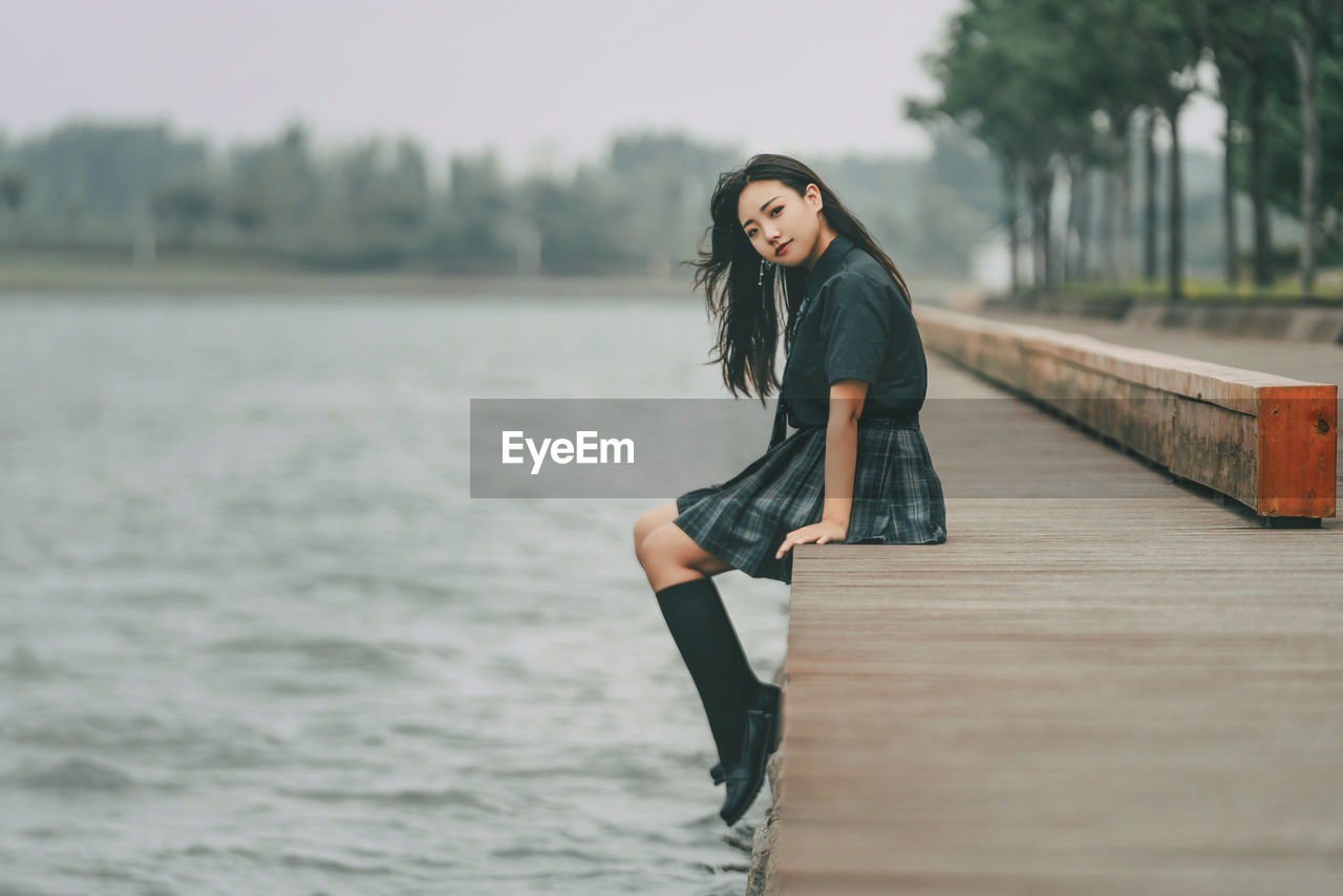 Damsel in uniform by a lake on a cloudy day