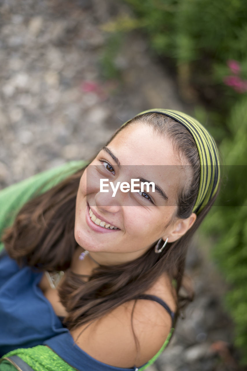 High angle portrait of smiling young woman sitting outdoors