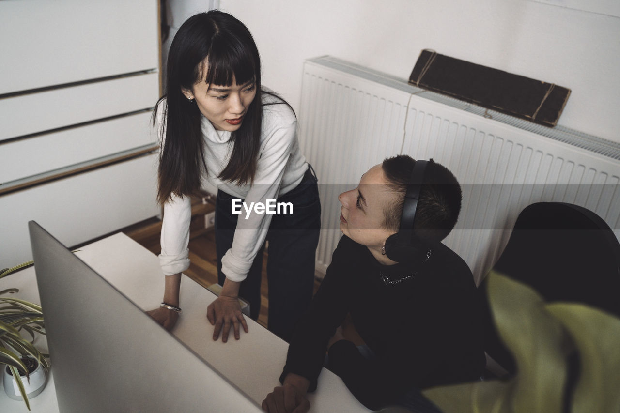 Businesswomen talking while working on computer at workplace