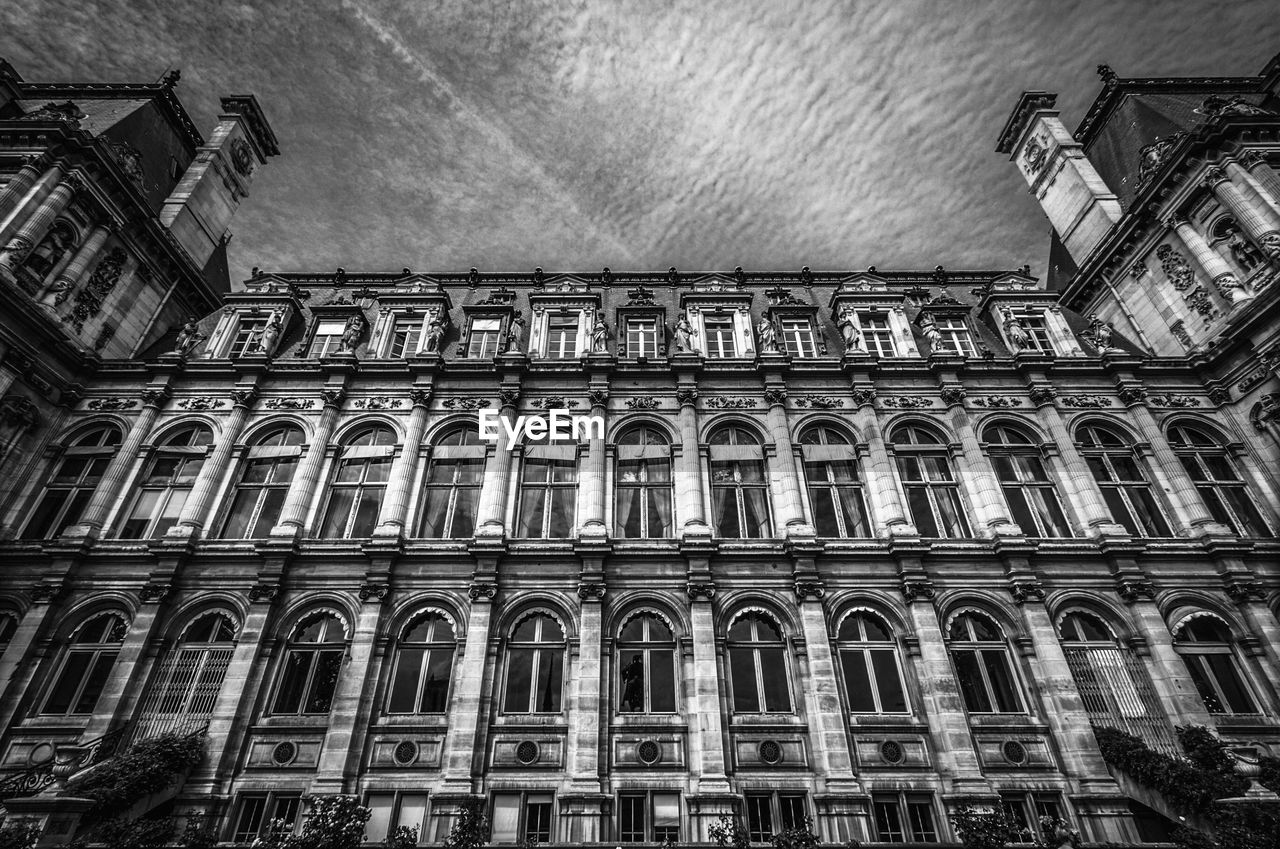 Low angle view of hotel de ville against cloudy sky