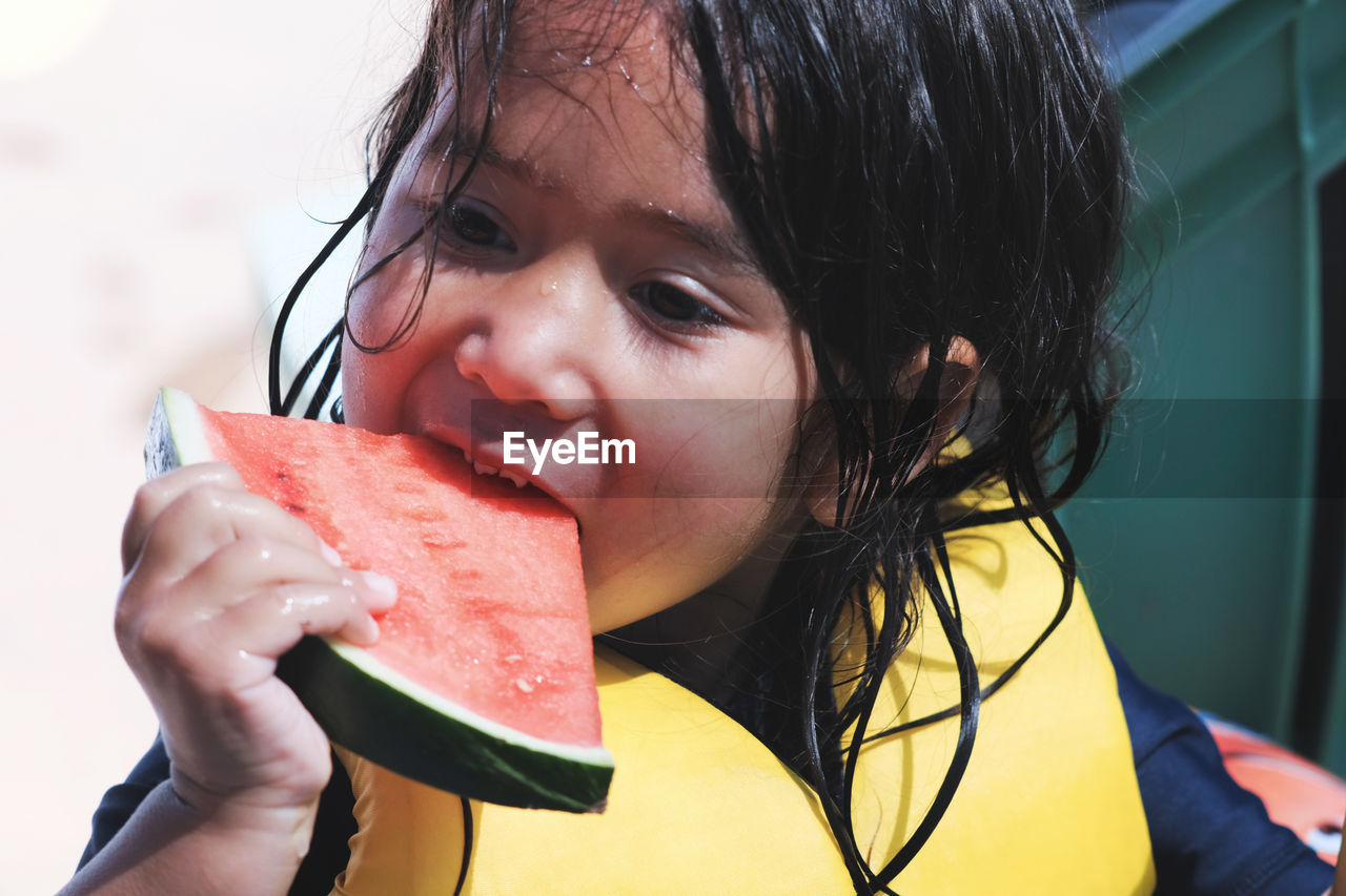 Close-up of wet girl eating watermelon