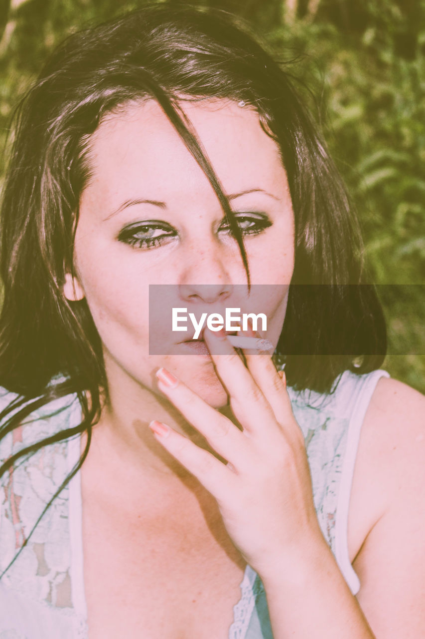 Close-up of young woman smoking in field