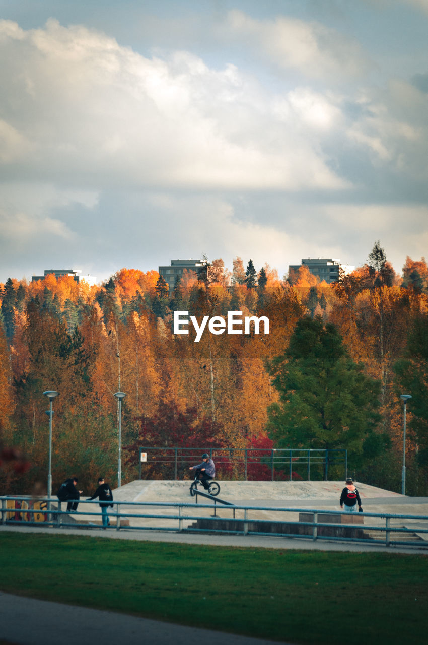 PEOPLE ON PARK DURING AUTUMN AGAINST SKY