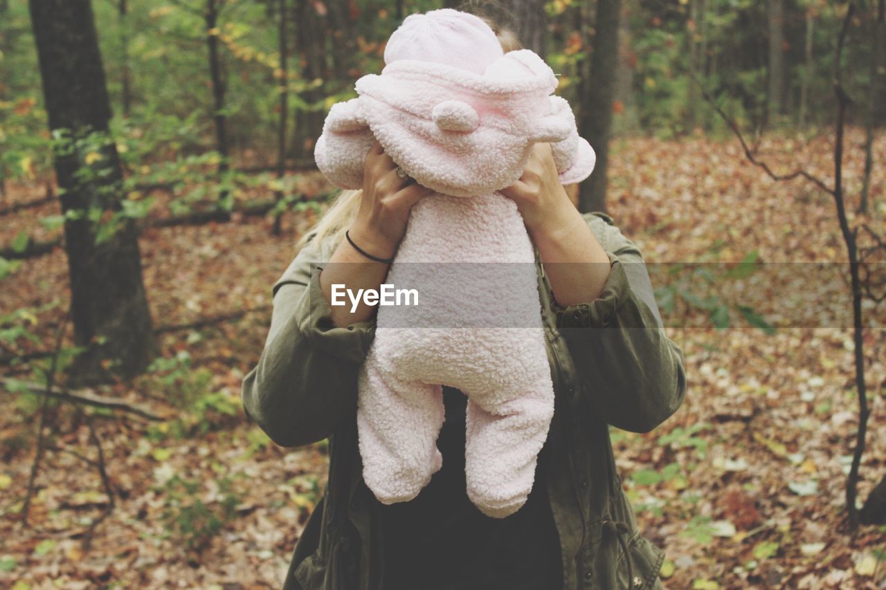 Mother holding baby amidst trees at forest