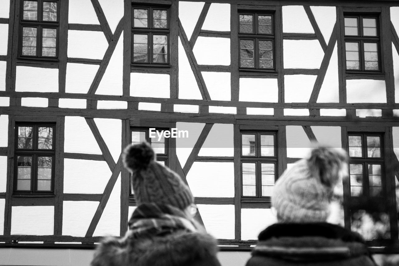 REAR VIEW OF PEOPLE SITTING ON BENCH IN BUILDING