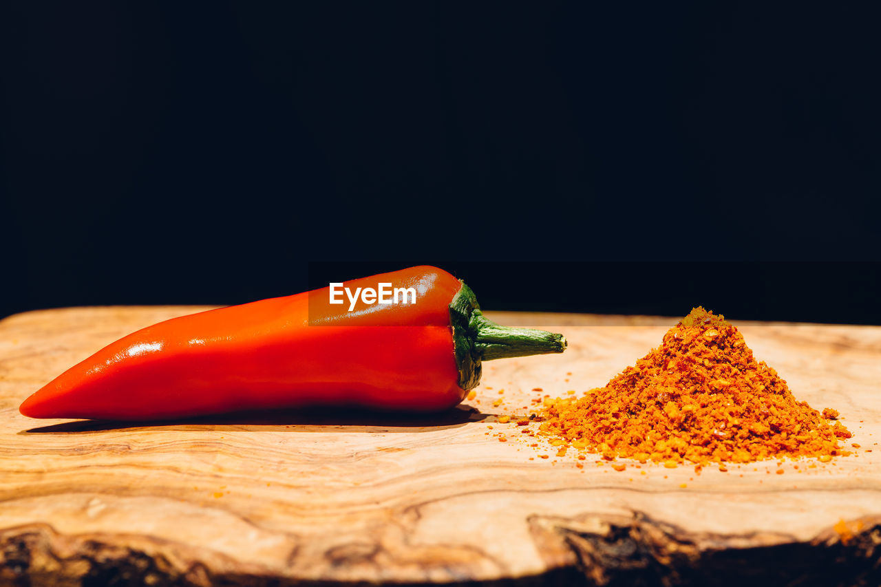 CLOSE-UP OF RED CHILI PEPPER AGAINST BLACK BACKGROUND