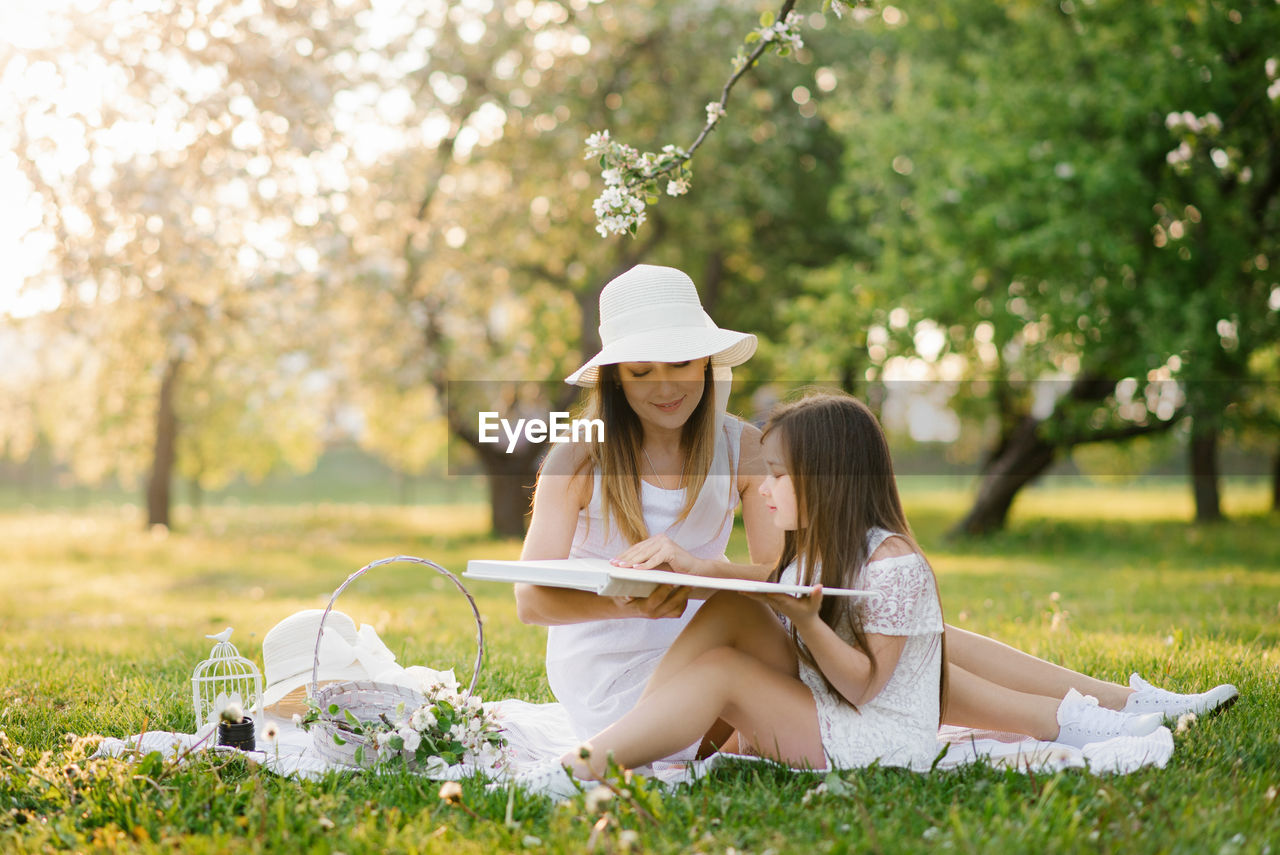 Caucasian family, mother and daughter together watching a family photo album in spring at a picnic