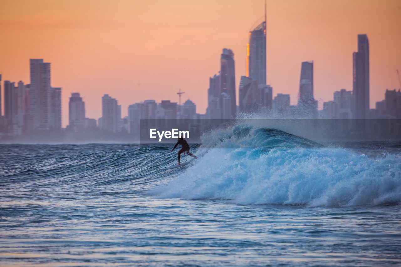 Scenic view of sea by buildings against sky during sunset