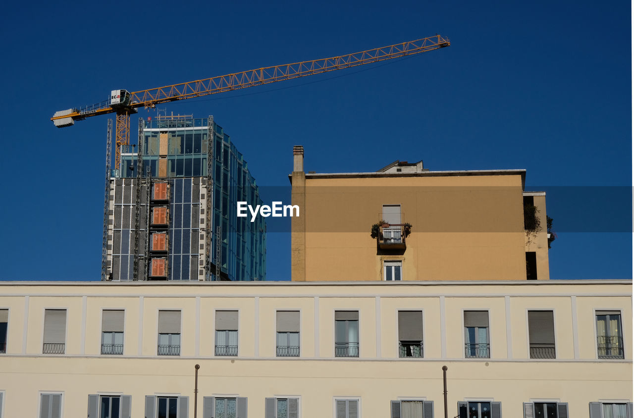LOW ANGLE VIEW OF BUILDING AT CONSTRUCTION SITE AGAINST BLUE SKY