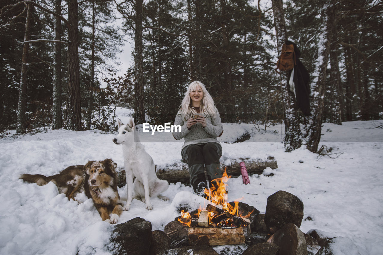 Woman sitting near log fire at winter