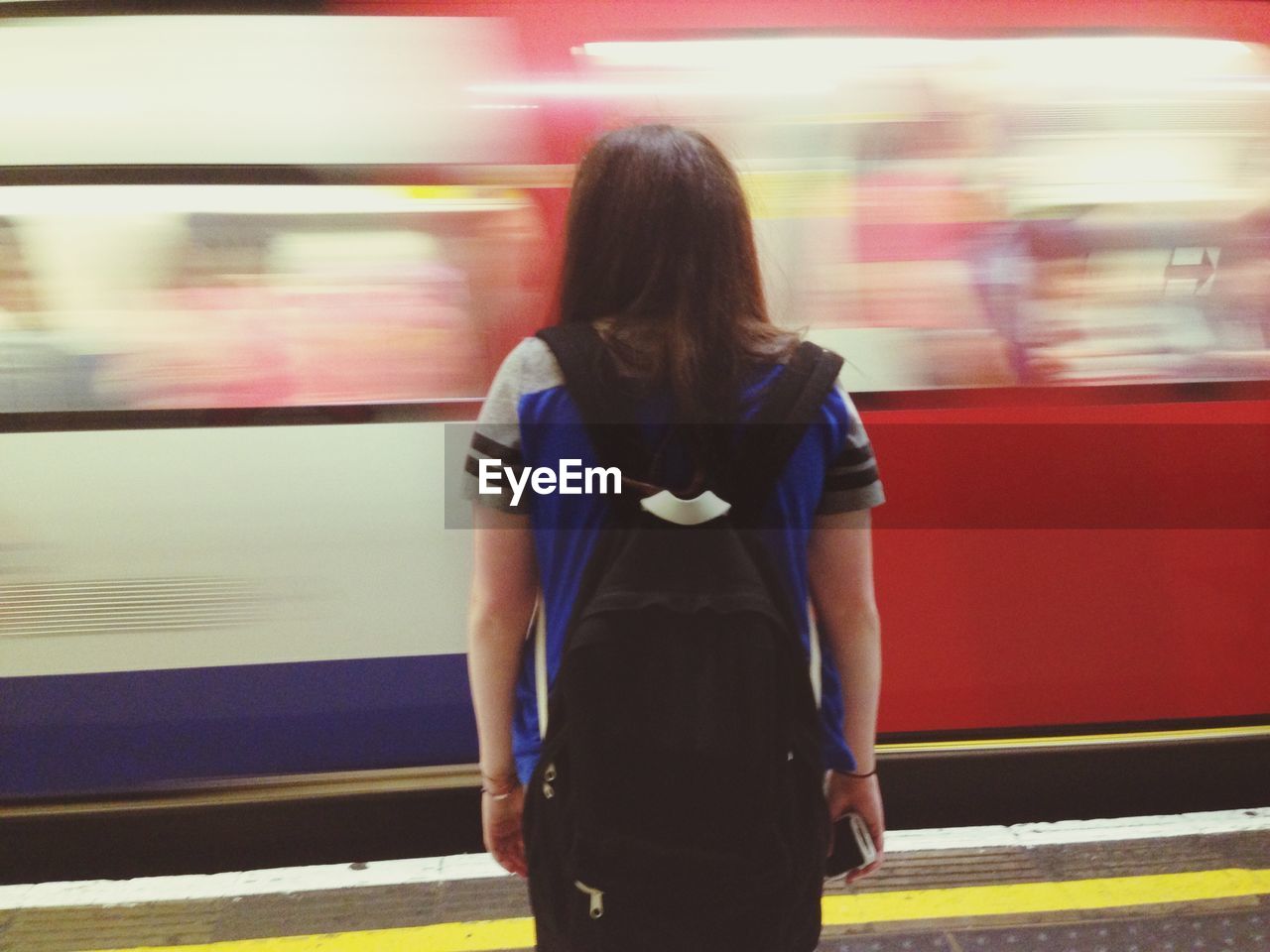 Girl with backpack in front of train