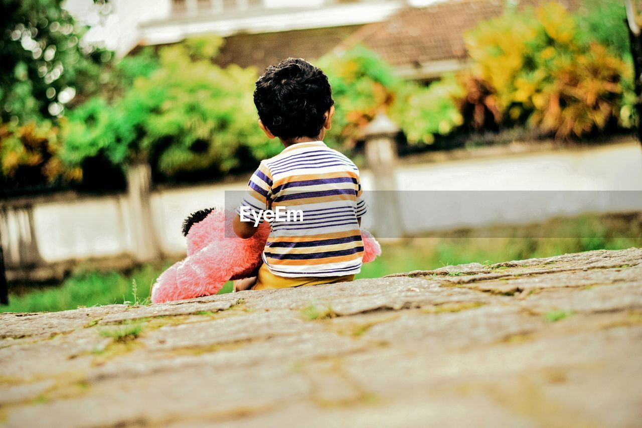 Rear view of boy sitting outdoors