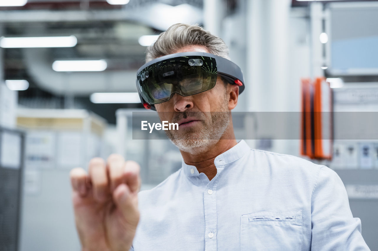 Businessman using augmented reality eyeglasses at factory