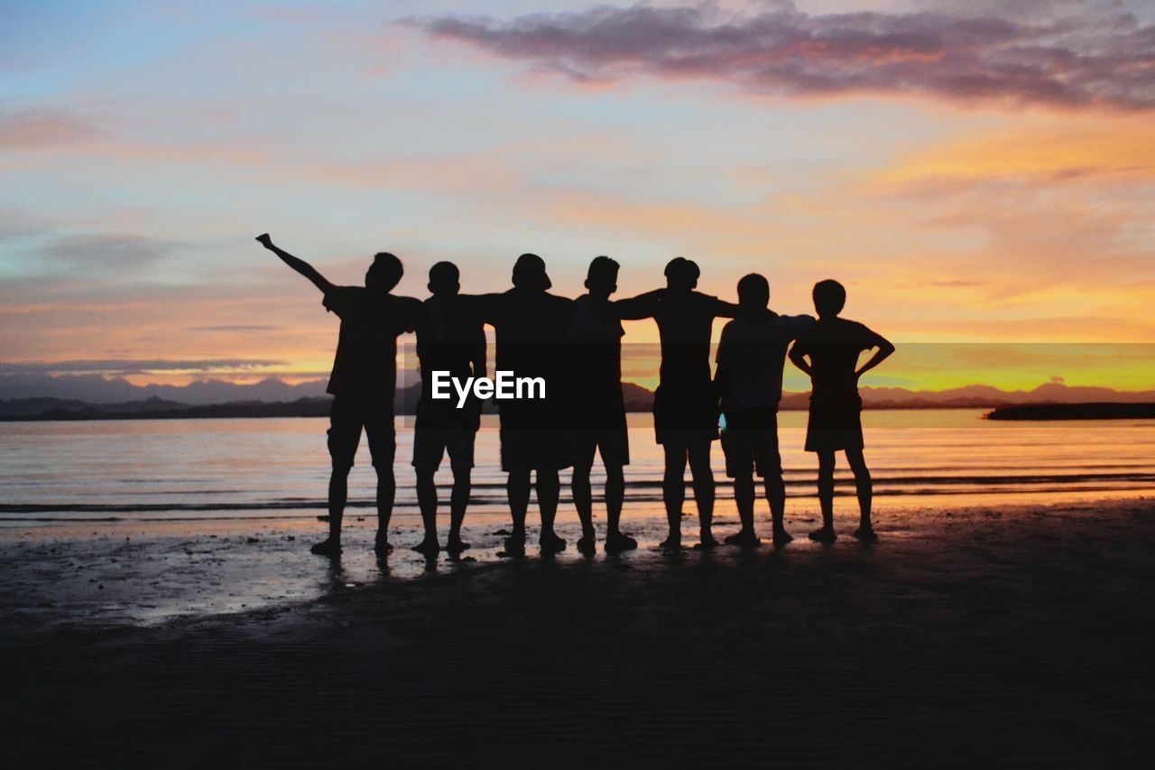 Silhouette people standing against sea during sunset