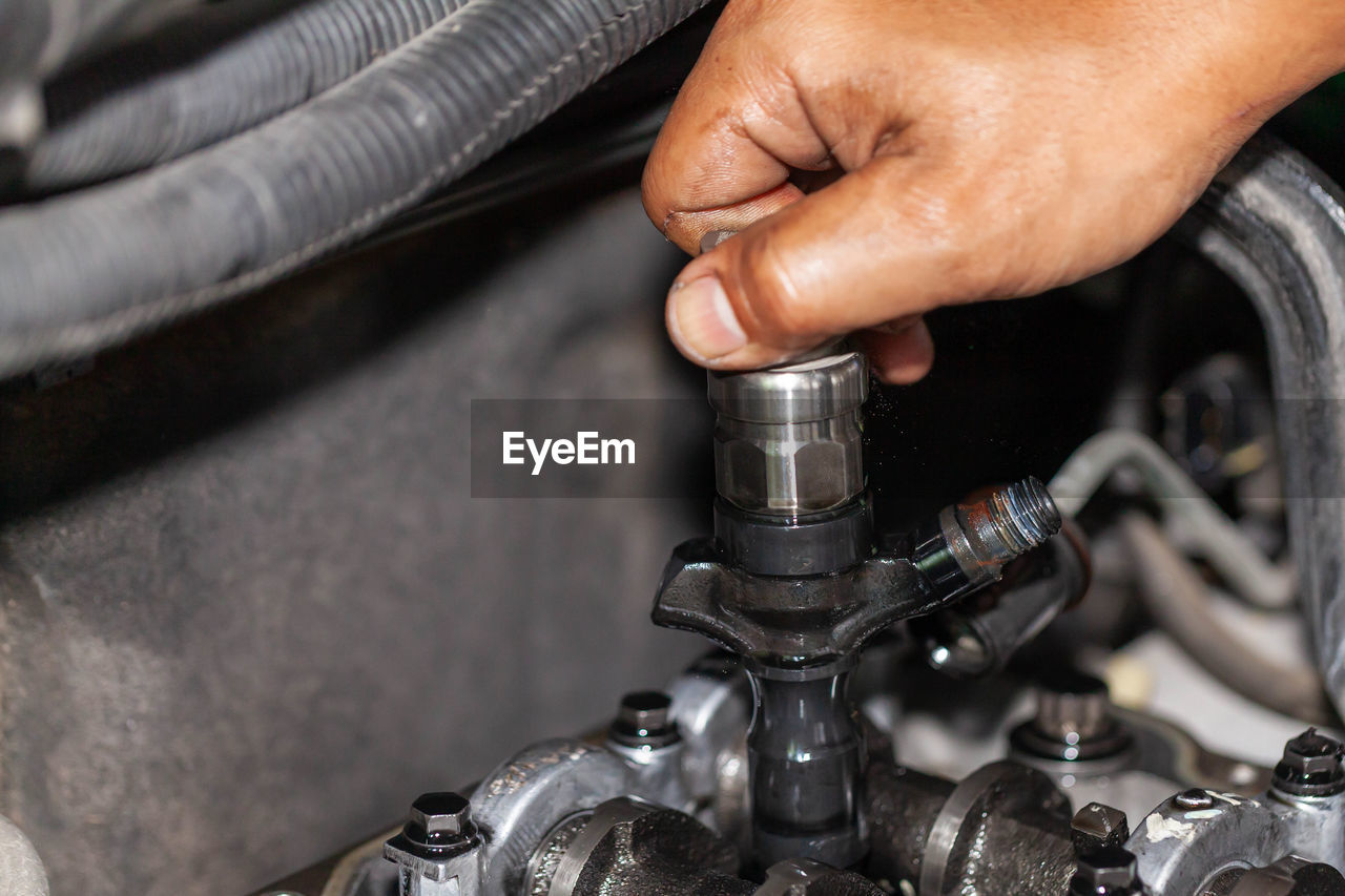 Cropped hand of person examining car in garage