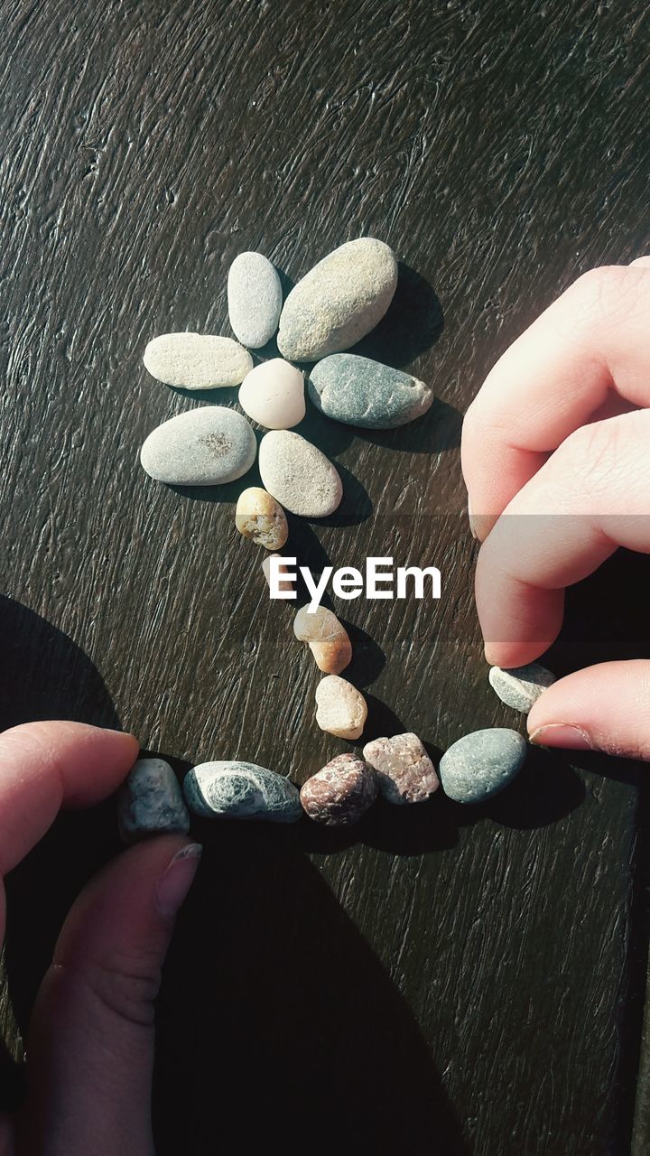 CLOSE-UP OF PERSON HOLDING PEBBLES