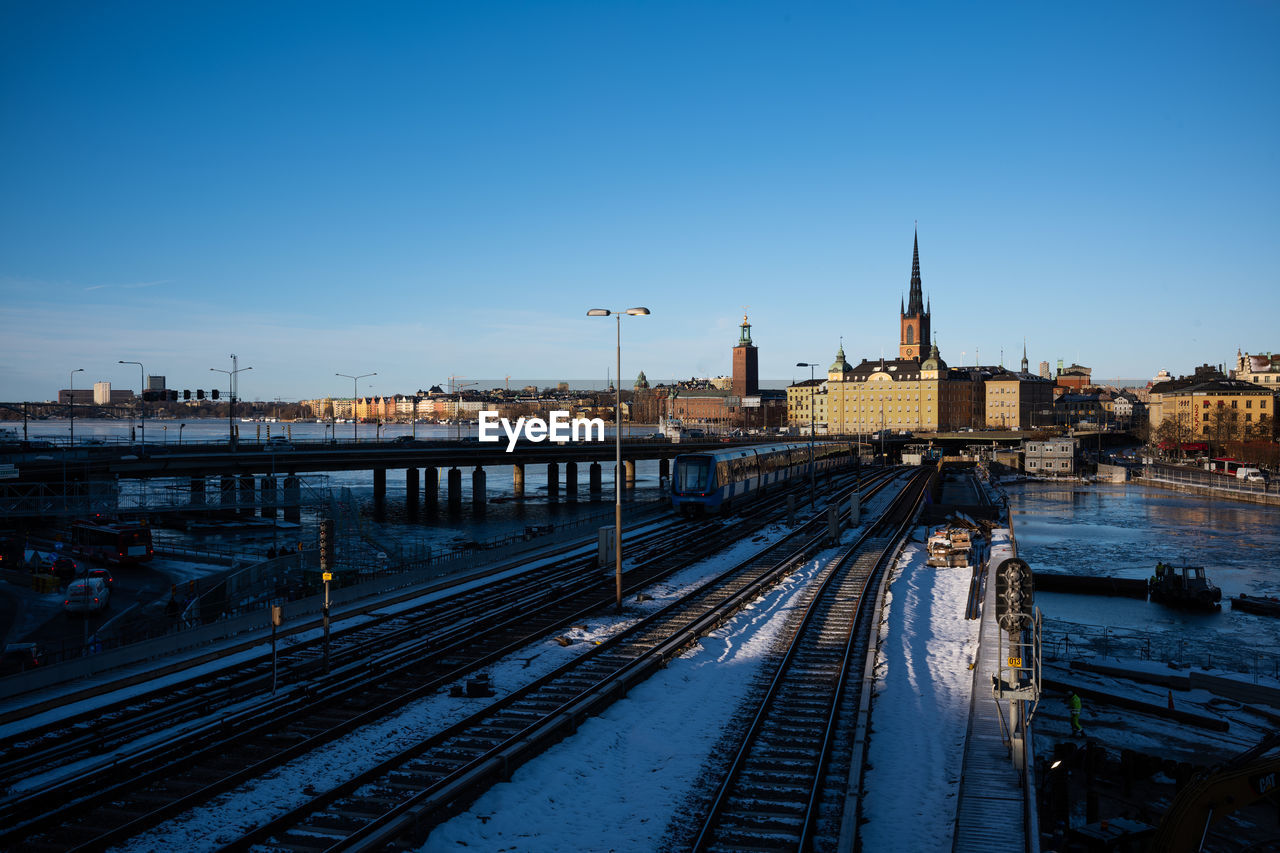 High angle view of railroad tracks by river against blue sky