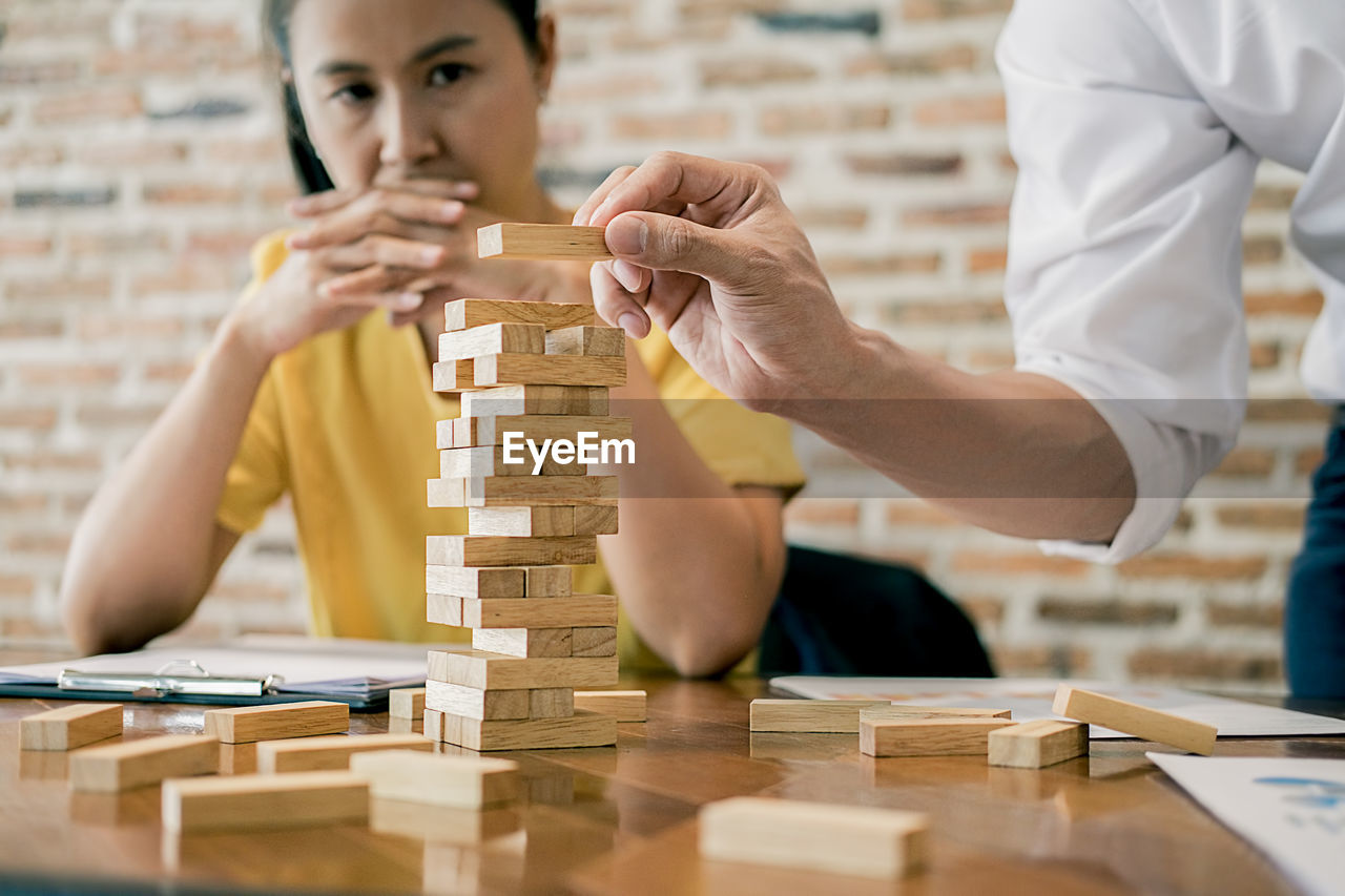 Woman looking at man stacking toy blocks at table