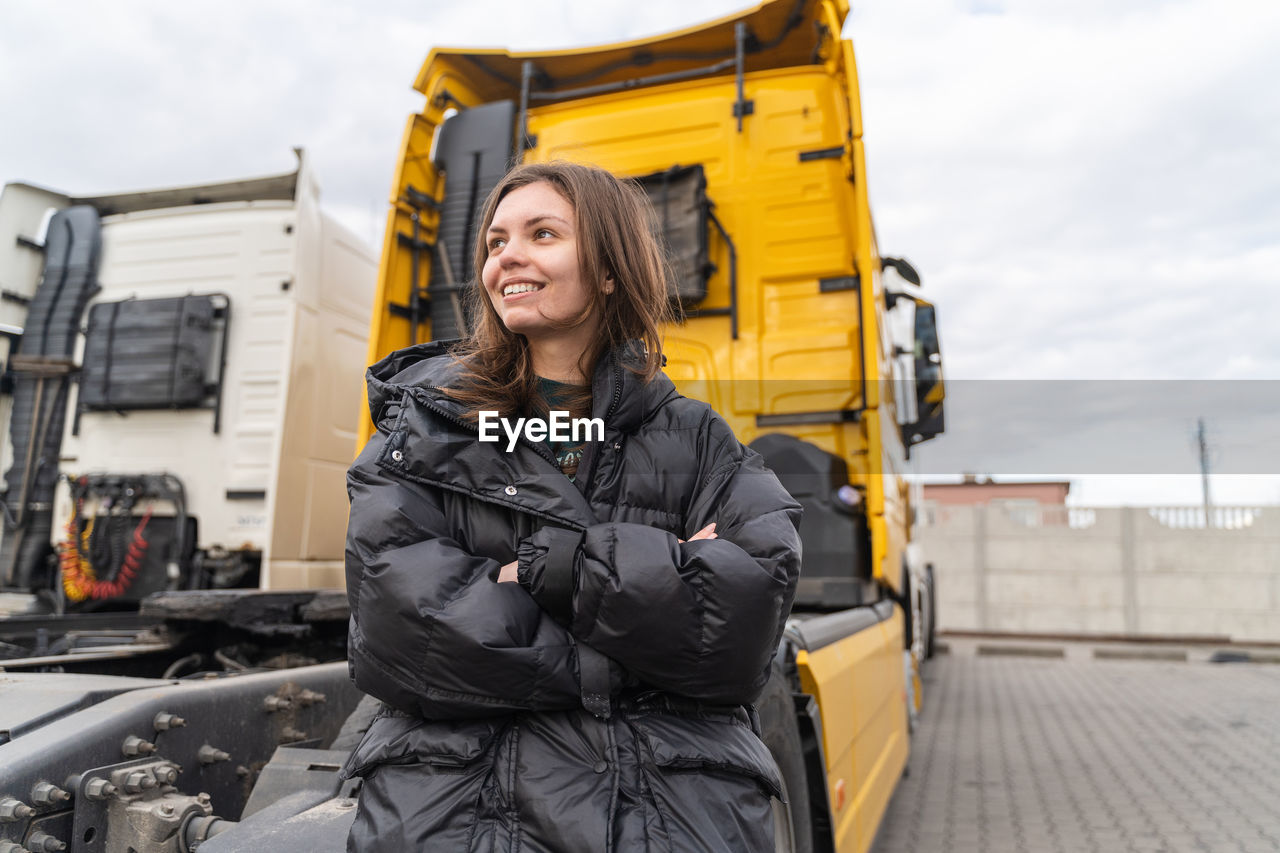 Happy mature woman standing against truck