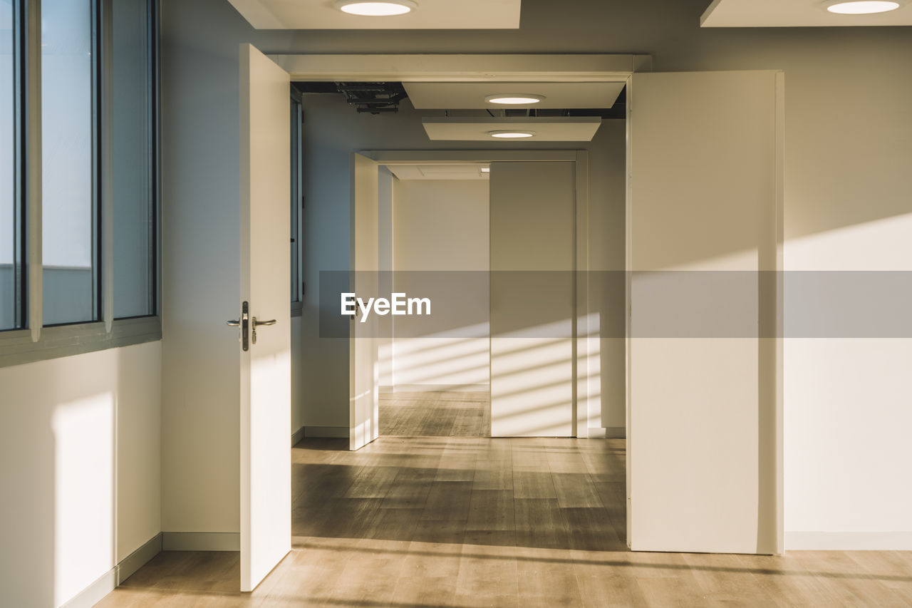 Interior of empty spacious loft hallway with geometrical shadows and sunlight on white walls