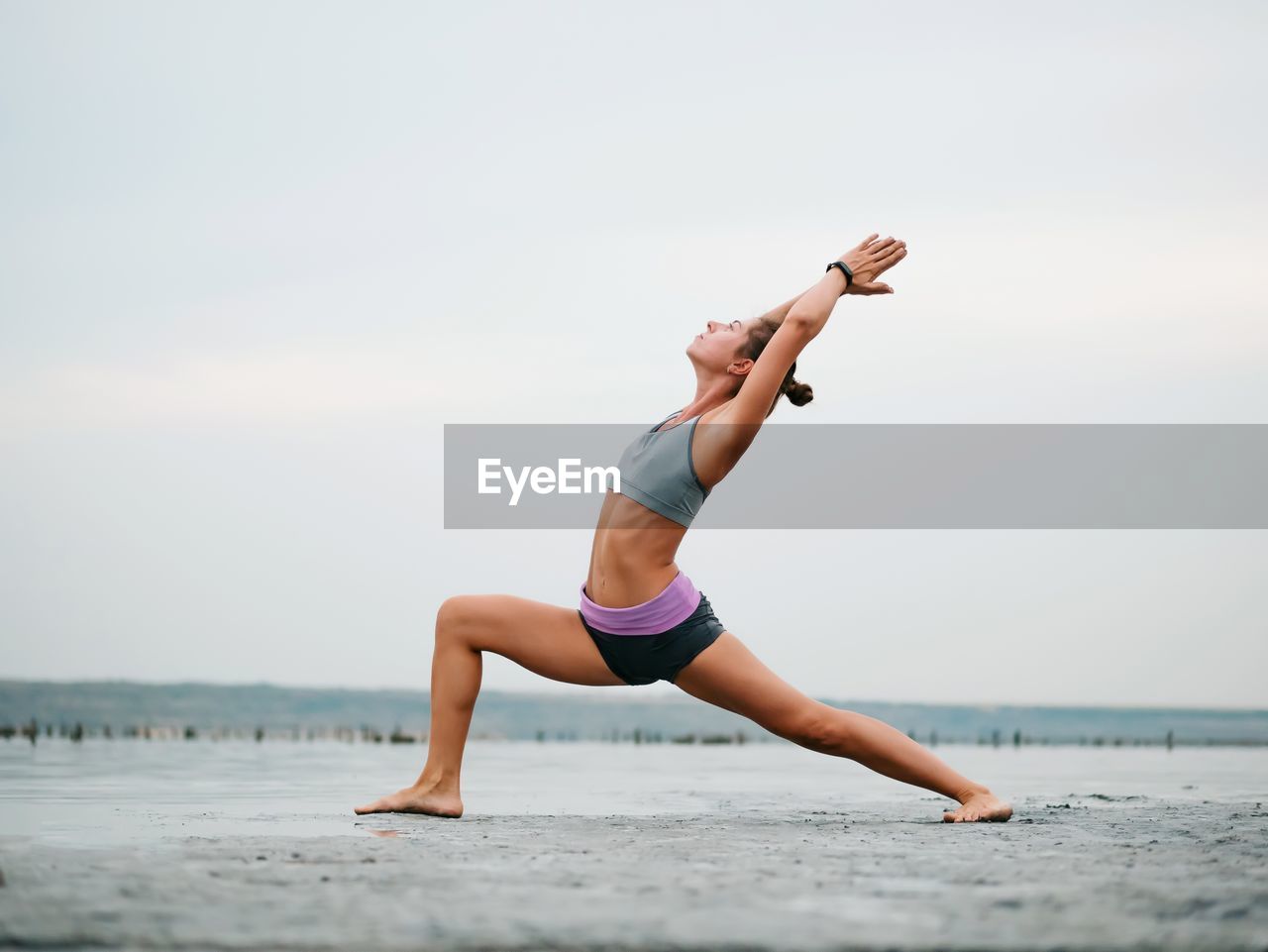 Full length of young woman at beach against clear sky