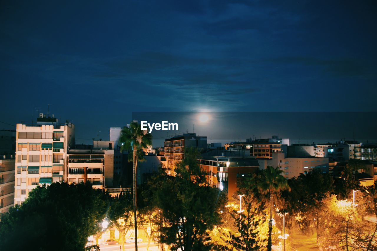 Illuminated buildings in city against sky