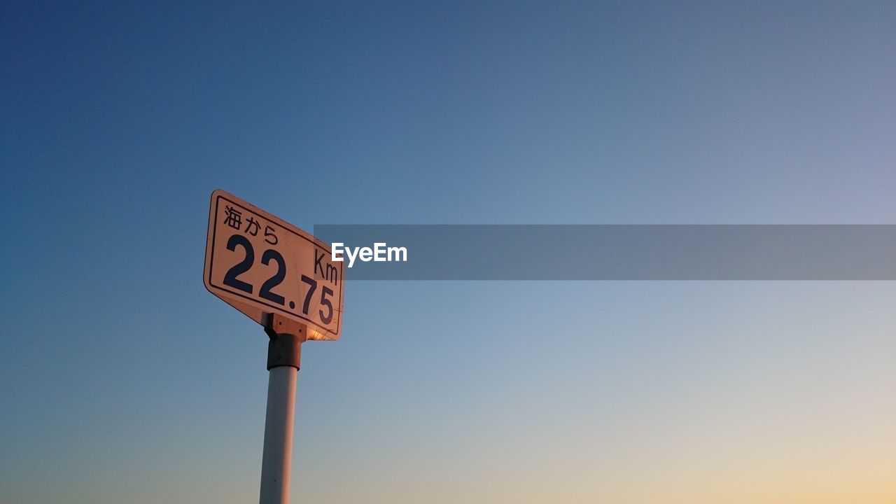 Low angle view of distance marker against clear sky