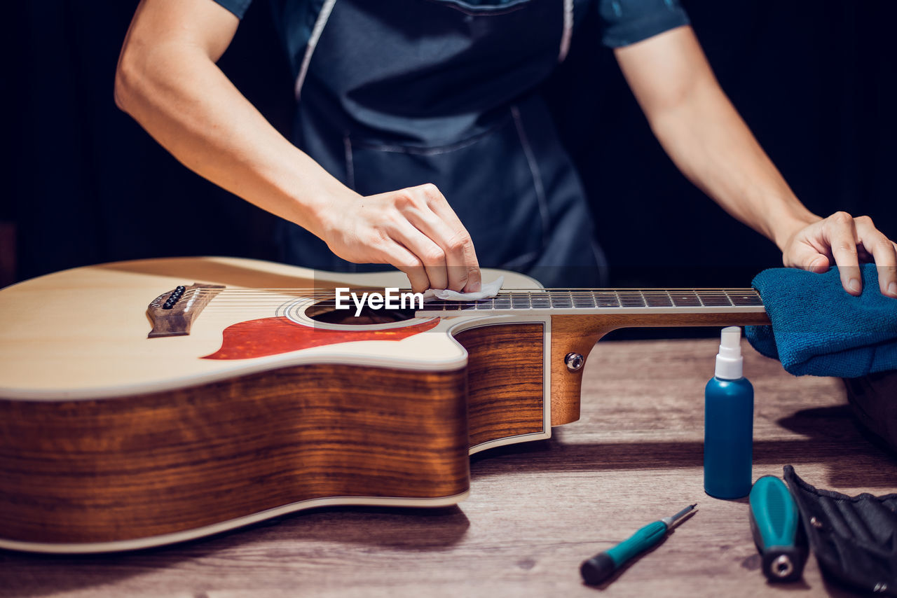 Midsection of man repairing guitar