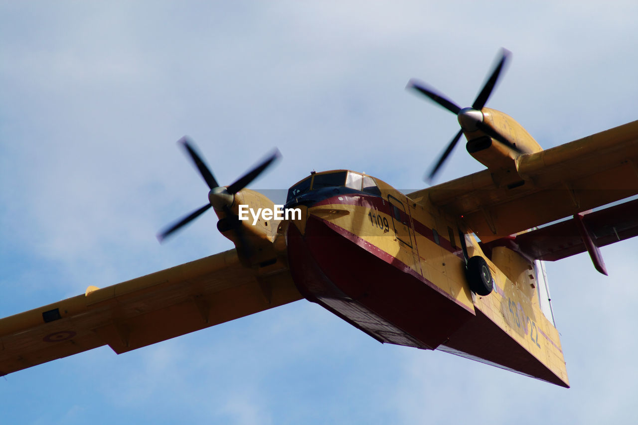 LOW ANGLE VIEW OF AIRPLANE FLYING AGAINST CLOUDY SKY