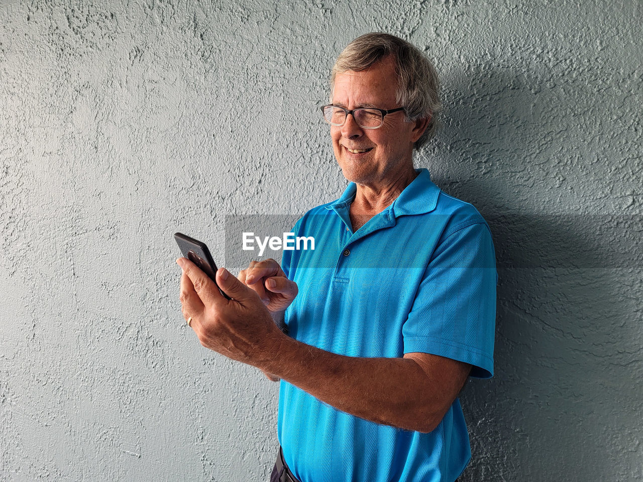 Happy retired grandfather on mobile device having a video chat with his grandkids.