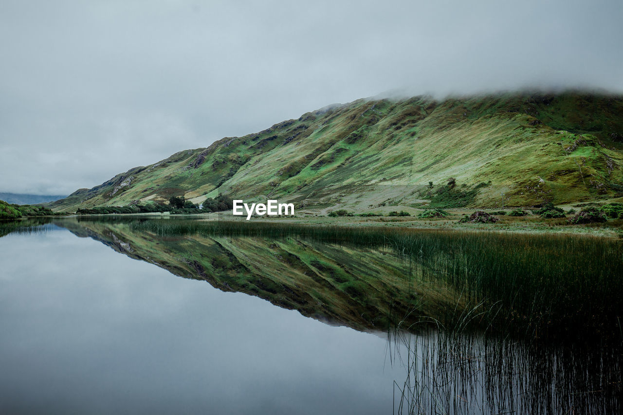 Scenic view of lake by mountain against sky