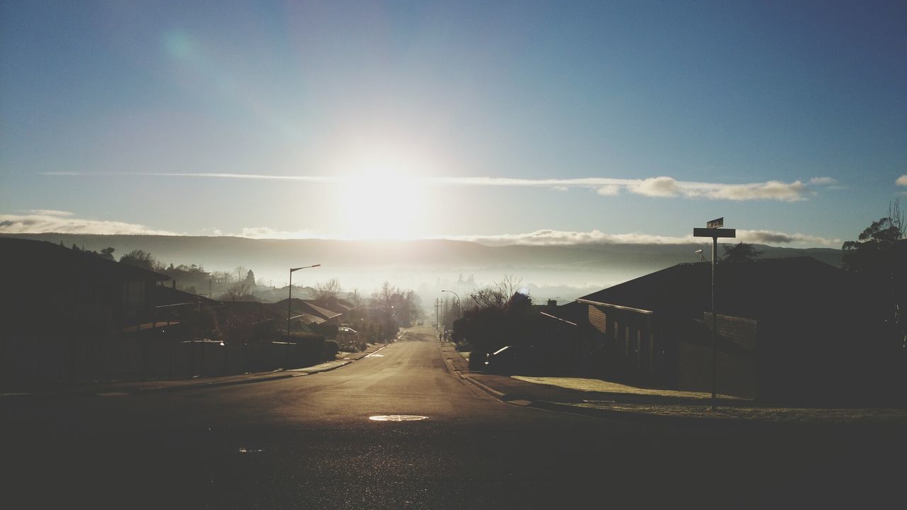 Empty road amidst houses against sky