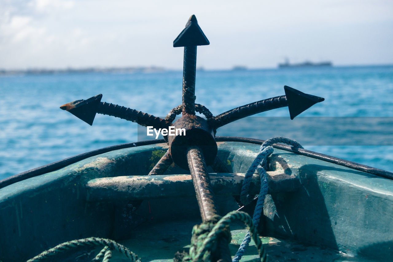 CLOSE-UP OF RUSTY WHEEL AGAINST SEA