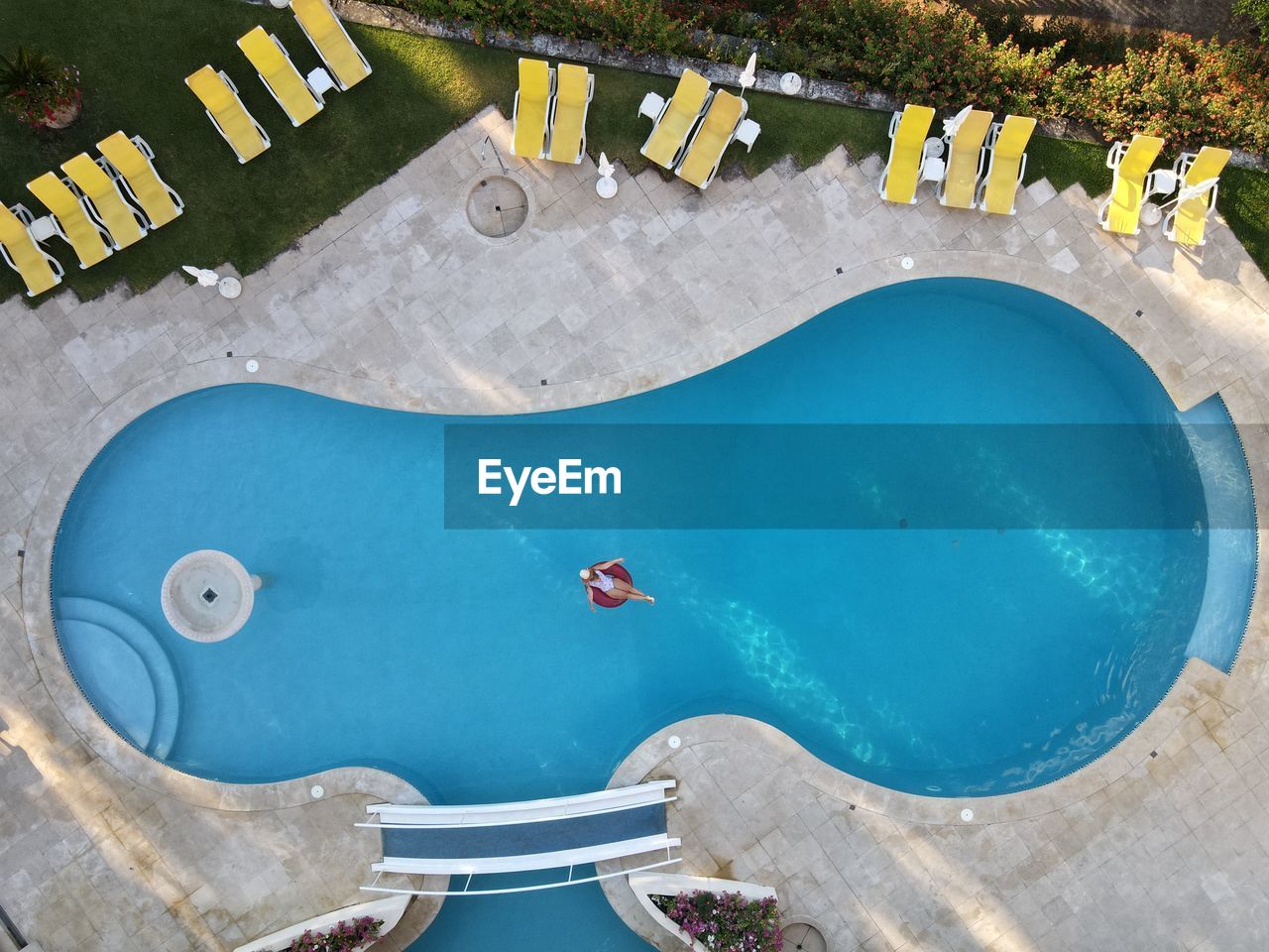 Aerial view of woman sitting on poo raft in swimming pool