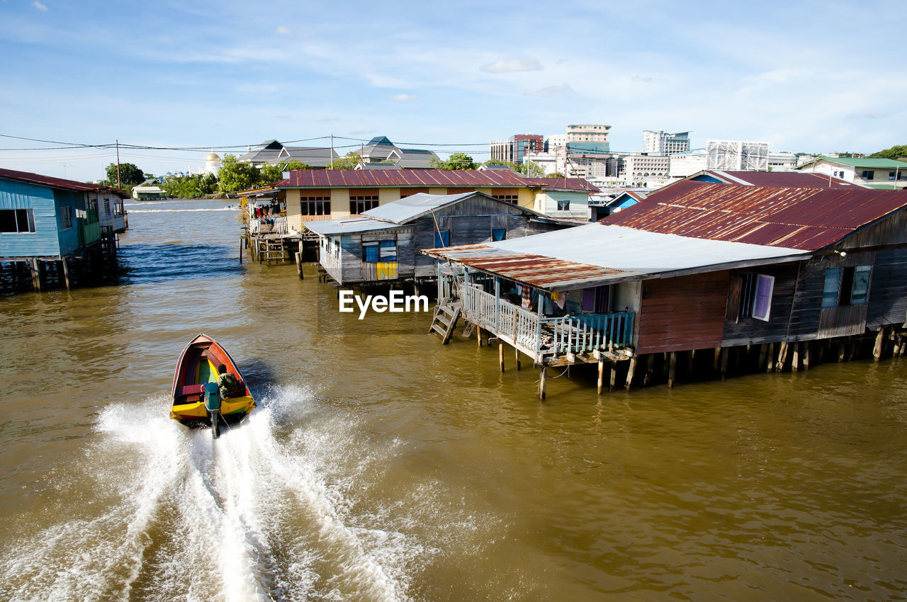 BOAT ON RIVER AGAINST BUILDINGS