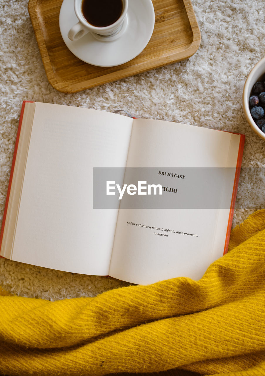 HIGH ANGLE VIEW OF COFFEE CUP WITH BOOK ON TABLE