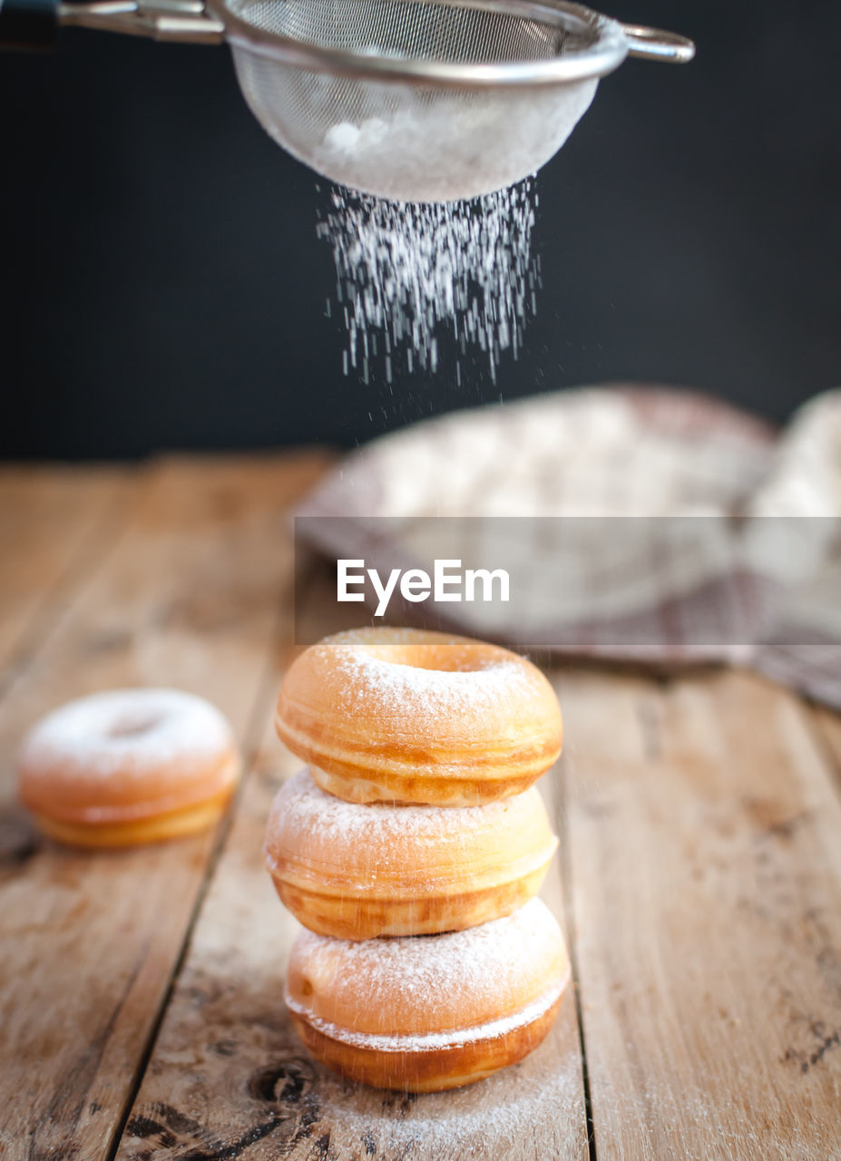 Stacked donuts with powdered sugar on wooden background