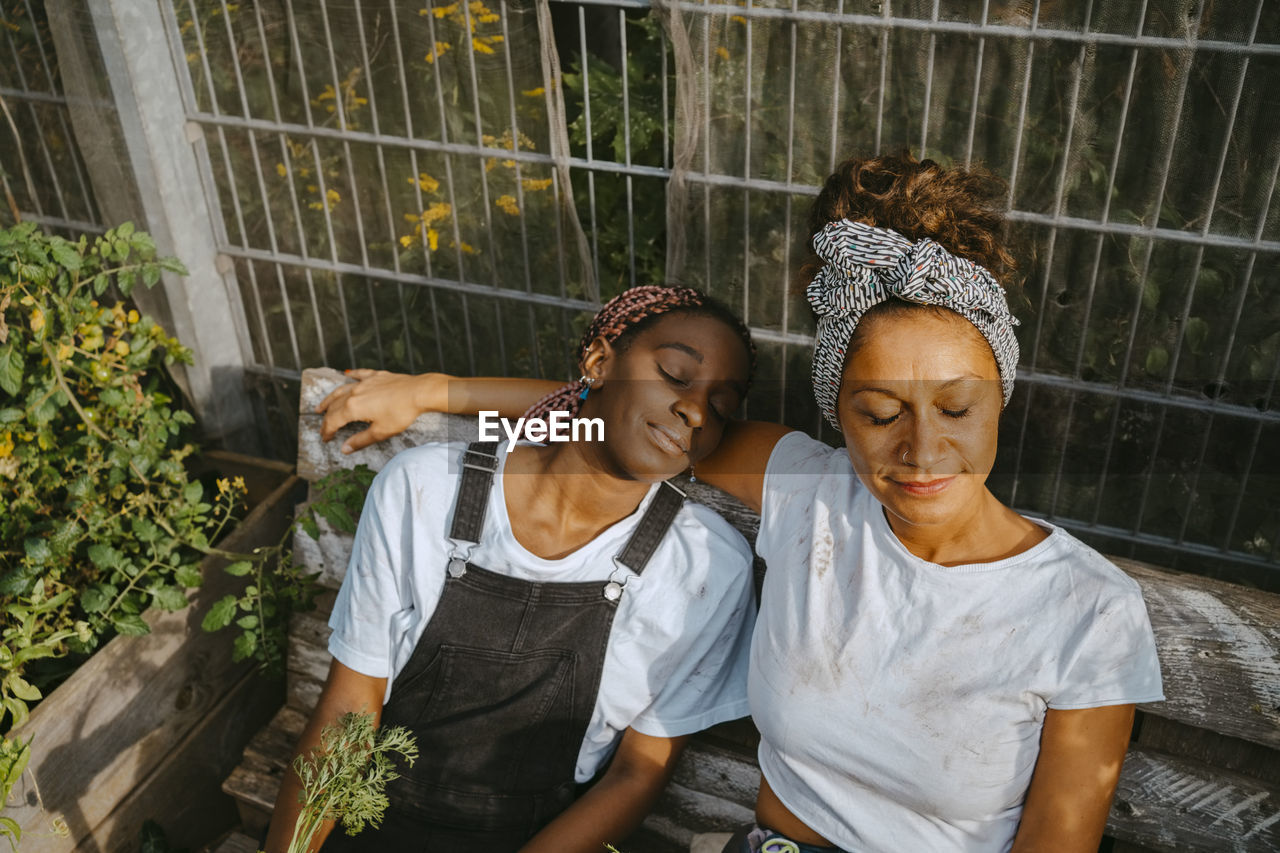 Female volunteers with eyes closed relaxing at community garden