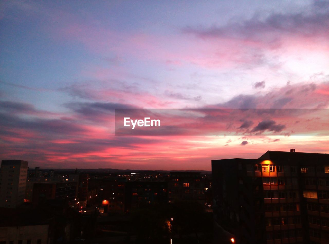 HIGH SECTION OF SILHOUETTE BUILDINGS AGAINST SUNSET SKY