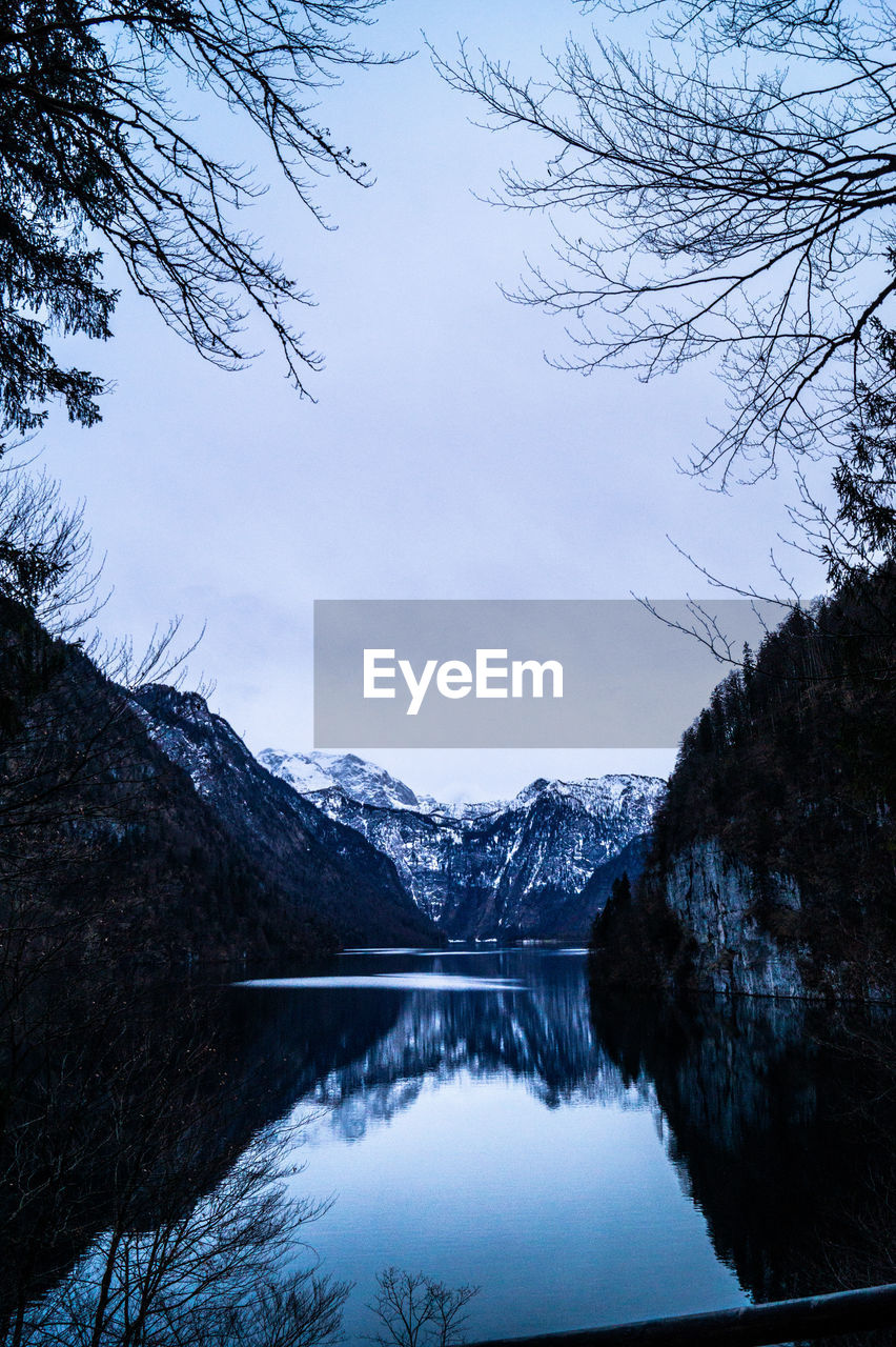 Scenic view of lake by snowcapped mountains against sky