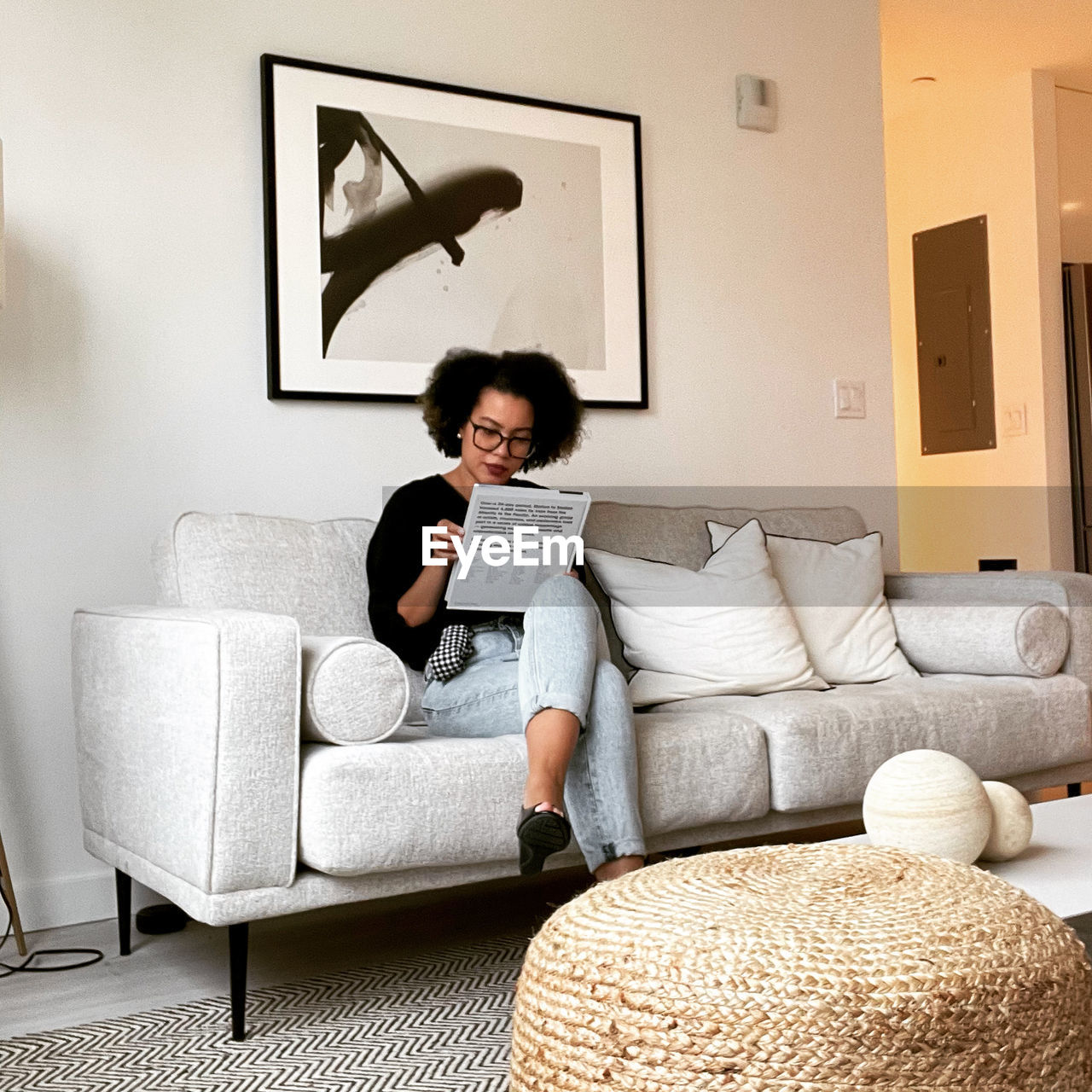portrait of young woman using digital tablet while sitting on sofa at home