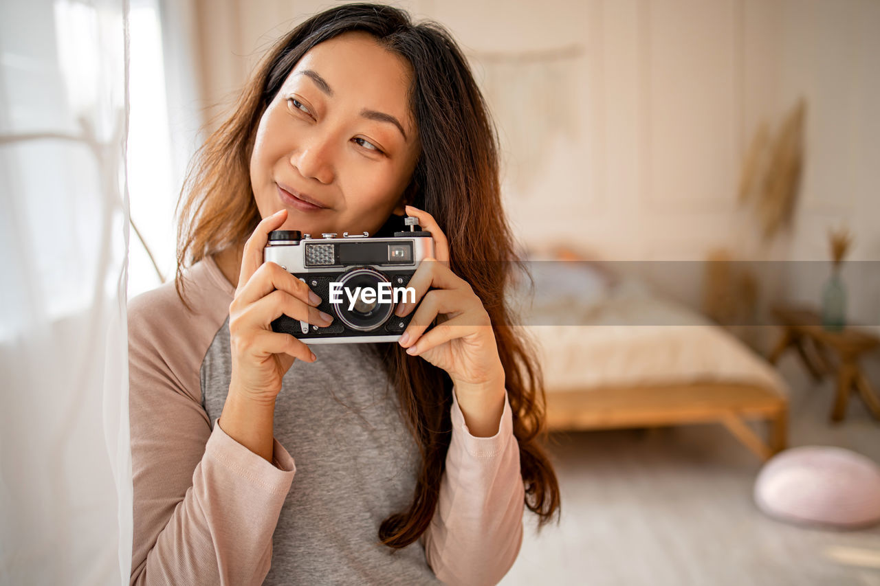 Portrait of young woman photographing with camera