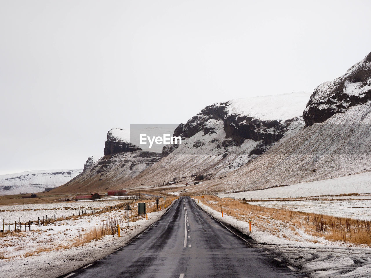 Road amidst snowcapped mountains against clear sky