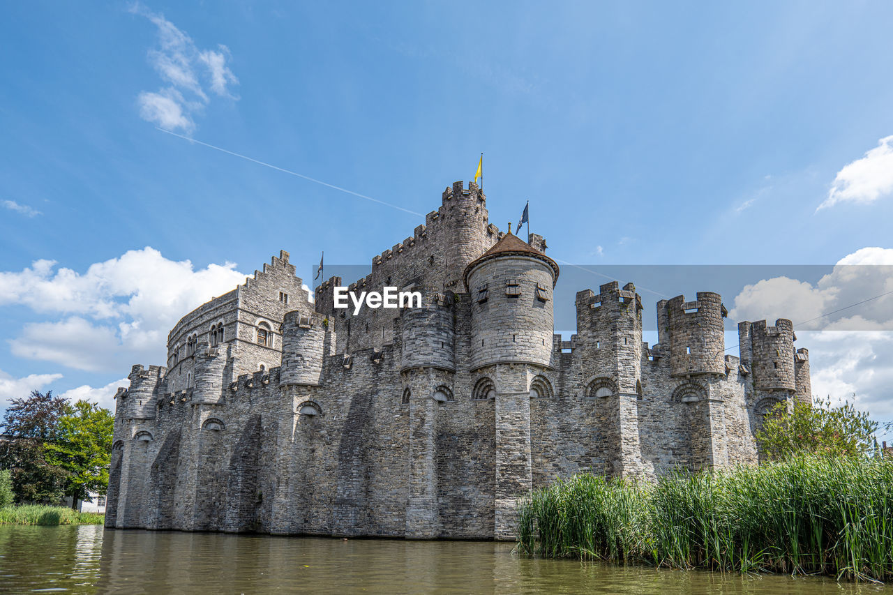 architecture, sky, castle, built structure, water, travel destinations, history, château, the past, nature, building, travel, building exterior, cloud, historic site, tourism, moat, plant, no people, religion, outdoors, ancient, river, blue, tree, water castle, reflection, landscape, medieval, day, old, landmark, city, tower, place of worship, trip, holiday
