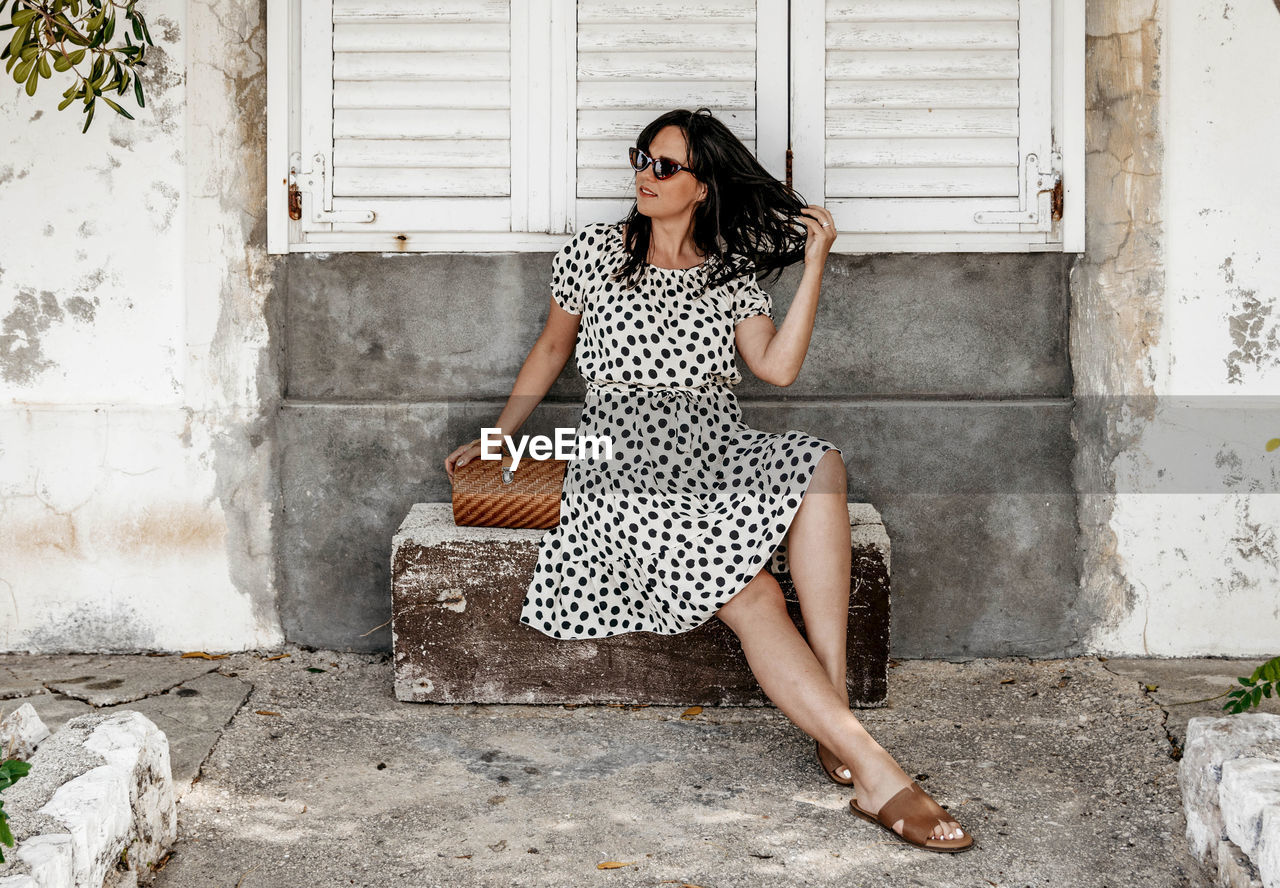 Portrait of young woman sitting on stone bench. summer, lifestyle, dress, fashion.