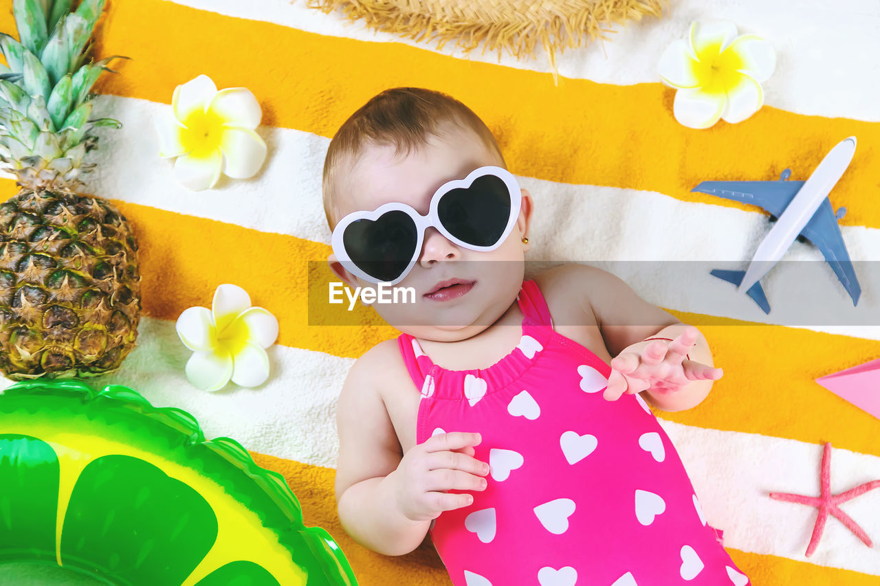 portrait of smiling young woman wearing sunglasses while sitting against christmas tree